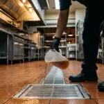 Trabajador vertiendo líquido en la coladera de una cocina industrial